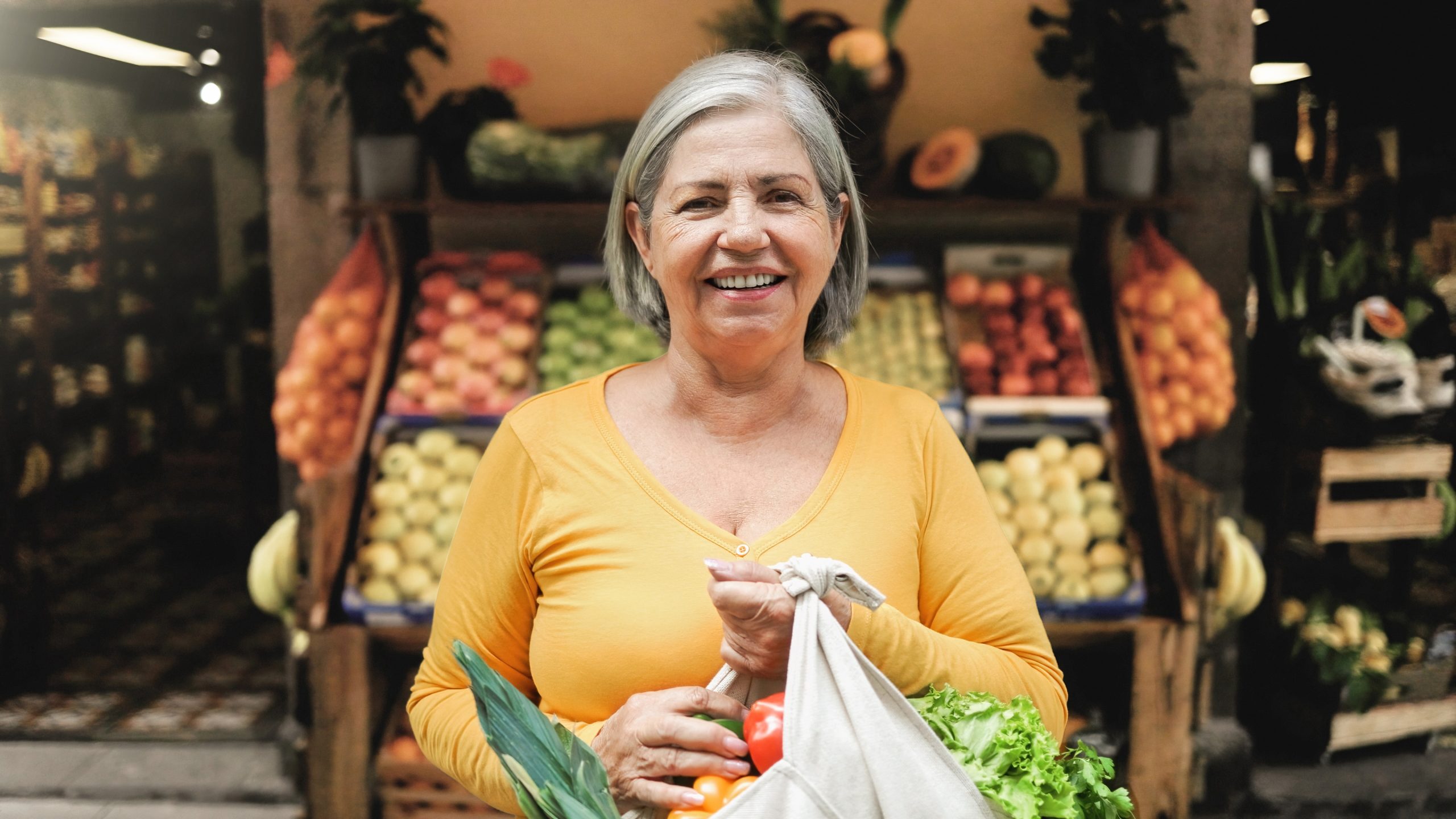 Vrouw met boodschappentas voor groentekraam