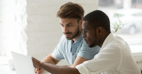 Twee mannen bekijken samen een webpagina op de laptop